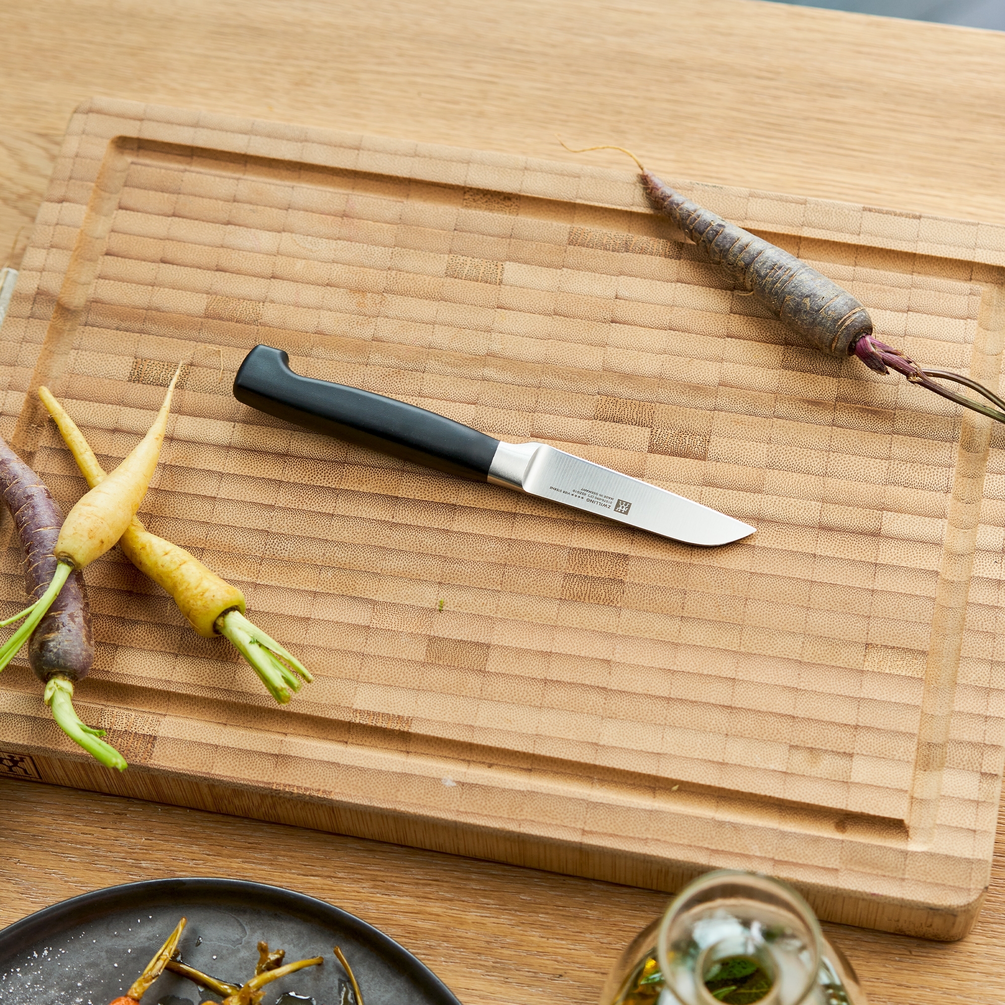 Kleines Gemüsemesser auf Schneidebrett mit Möhren